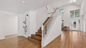Ein geräumiges Zimmer mit einer Holztreppe, weißen Wänden und einem großen Fenster.