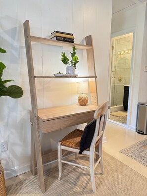 A wooden desk with a chair, a potted plant, and a lamp.