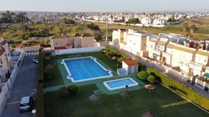 A residential area with a swimming pool, a tennis court, and a view of a cityscape.
