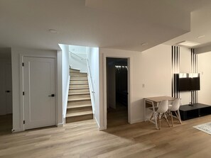 Ein modernes Interieur mit Treppe, Essbereich mit Stühlen, Fernseher und Schrank.