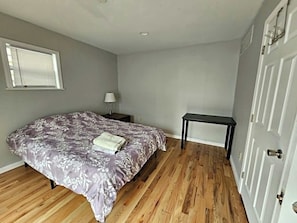 Une chambre à coucher avec un lit, une table de chevet, une lampe, une petite table et une porte.