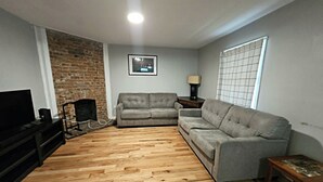 A living room with a fireplace, a sofa, a TV, and a wooden floor.