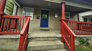 A house with a blue door, red railings, and a small porch.