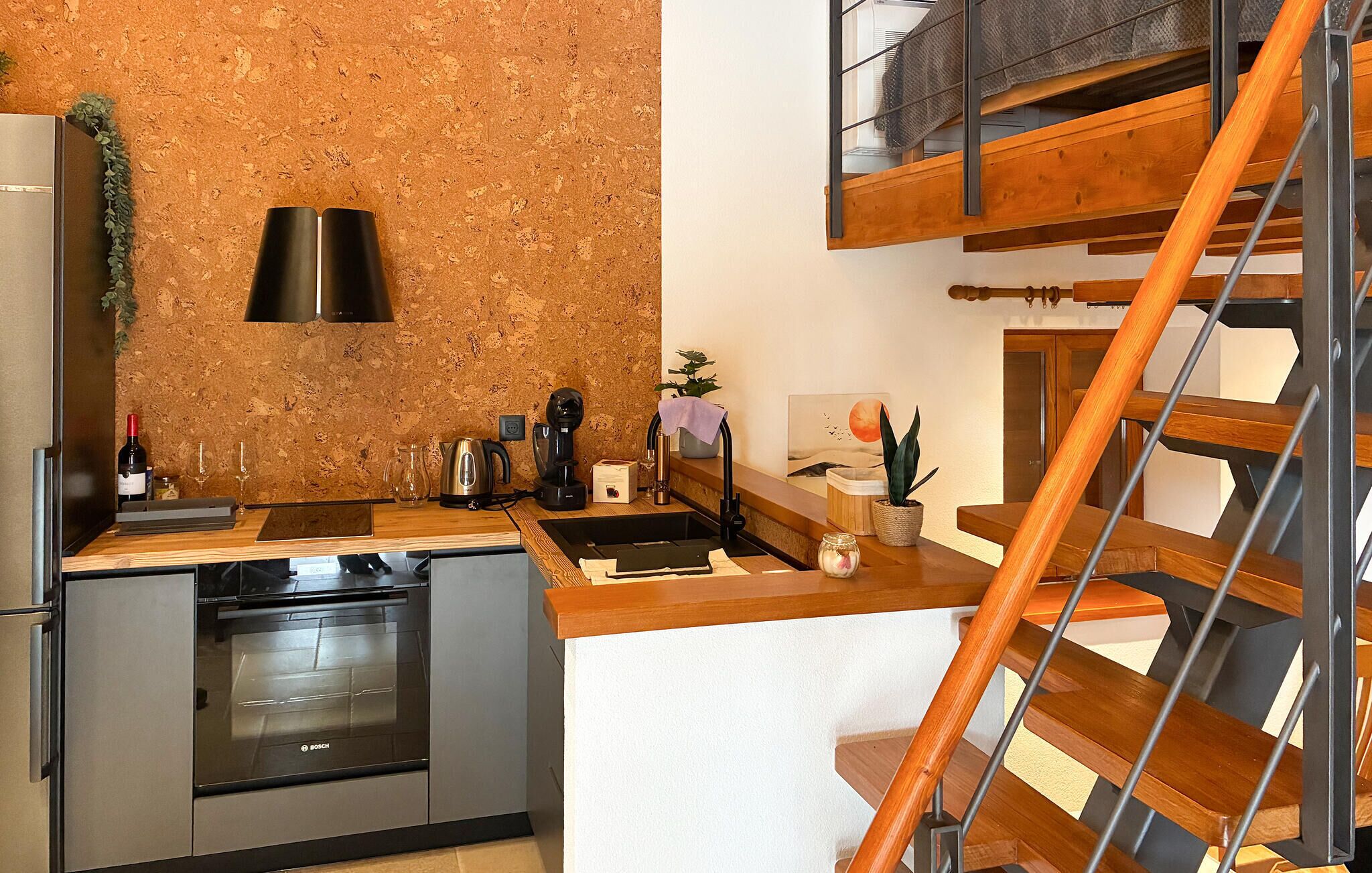 Una cocina compacta con horno Bosch, cafetera y lavabo.