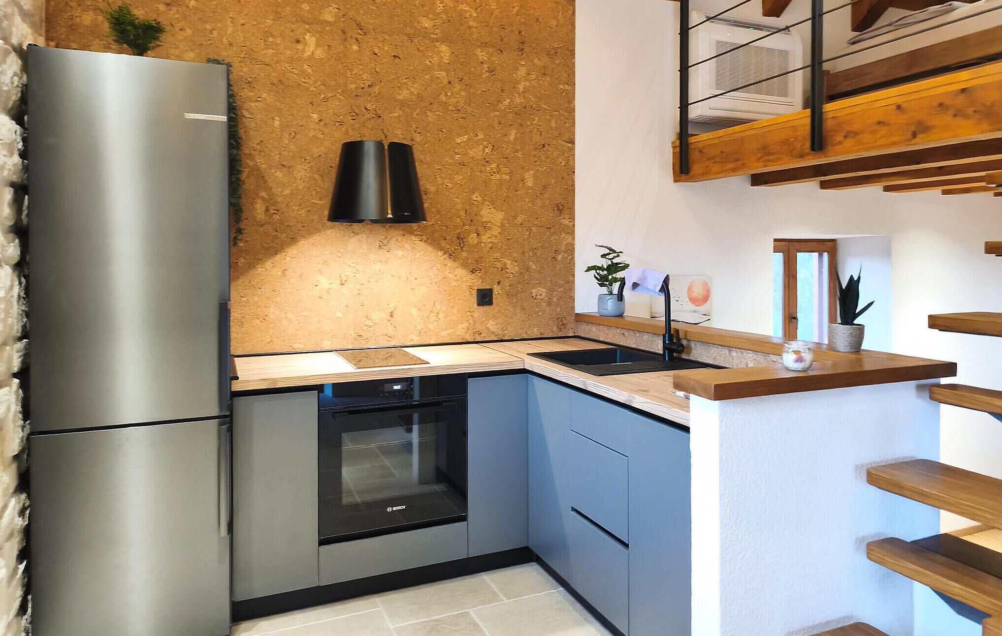 A kitchen with a stainless steel refrigerator, Bosch dishwasher, and a wooden countertop.