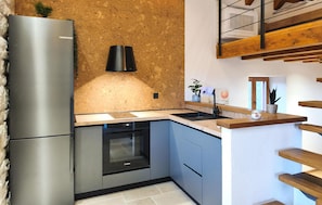 Eine Küche mit Edelstahl-Kühlschrank, Bosch Geschirrspüler und einer Holz Arbeitsplatte.