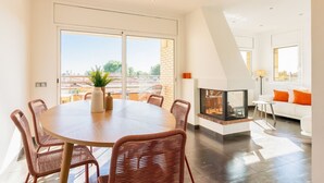 Un espace repas moderne avec une table ronde, des chaises en osier et une cheminée.
