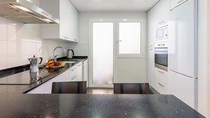 Une cuisine moderne avec des meubles blancs, un plan de travail noir, une machine à café et une fenêtre.