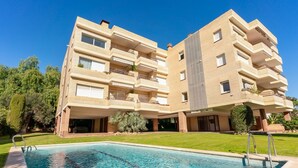 Un immeuble résidentiel à plusieurs étages, avec une piscine en premier plan.