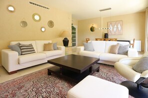 A living room with two white sofas, a dark coffee table, and a patterned rug. - Apartment Parc Del Mar (Sitges)
