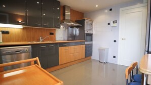 Una cocina moderna con lavavajillas, horno y microondas. Hay una mesa de madera con sillas.