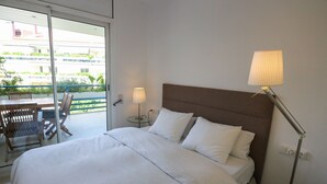 Habitación de hotel con cama, una mesa y sillas, una lámpara y vistas a zonas verdes.