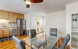 Una cocina moderna con armarios de madera, electrodomésticos de acero inoxidable y una mesa de comedor de vidrio con sillas.