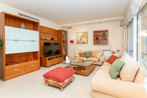 Una sala de estar moderna con televisor de pantalla plana, un conjunto de sofás, una mesa de centro y estanterías empotradas de madera.