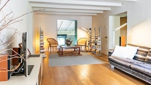 En moderne stue med sofa, sofabord, reoler og et spiseområde med stole.