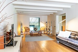 Ein modernes Wohnzimmer mit einer Couch, einem Couchtisch, einem Bücherregal und einem Essbereich mit Stühlen.