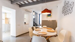 A modern dining area with a round table, white chairs, and a pendant light. - Casa Cipres - Three Bedroom Apartment, Sleeps 6 (Sitges)