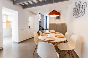 Una zona de dinar moderna amb una taula rodona, caires blancs i una làmpada penjant.