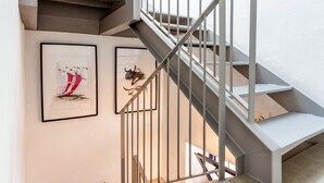A staircase with metal railings and a white wall with two framed artworks. - Casa Cipres - Three Bedroom Apartment, Sleeps 6 (Sitges)