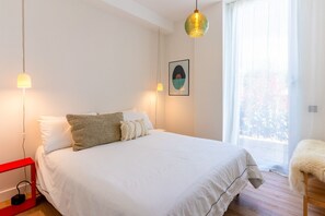 A bedroom with a bed, bedside lamps, a framed picture, and a window with curtains. - Casa Del Mar - Three Bedroom Apartment, Sleeps 6 (Sant Pere de Ribes)