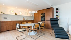 Une cuisine moderne avec des meubles en bois, une table de salle à manger ronde entourée de quatre chaises, et un fauteuil noir.