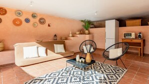 Una sala de estar con un sofá, dos sillones, una mesa de centro, un tapete estampado y platos decorativos en la pared.