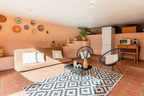 Ein Wohnzimmer mit einer Couch, zwei Sesseln, einem Couchtisch, einem gemusterten Teppich und dekorativen Tellern an der Wand.