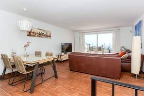 Ein modernes Wohnzimmer mit Essbereich, einem großen Fenster mit Blick und einem Flachbildfernseher.