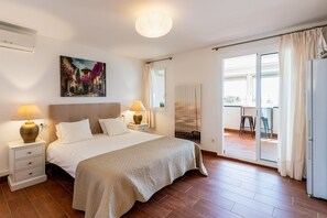 Ein Schlafzimmer mit Bett, Nachttischlampen, Heizkörper, Fenster und Blick ins Freie.