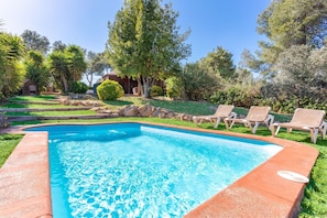 A rectangular swimming pool with a clear blue water surface, surrounded by a red border. There are three lounge chairs with beige cushions aligned along the pool's edge. - Casa Mokki - Three Bedroom Villa, Sleeps 7 (Olèrdola)