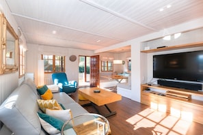 A modern living room with a sofa, a coffee table, a TV, and a blue armchair. - Casa Mokki - Three Bedroom Villa, Sleeps 7 (Olèrdola)