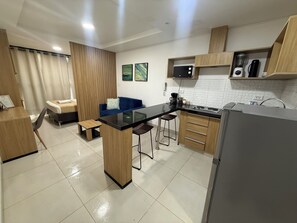 Eine moderne Küche mit einer zentralen Kochinsel, Holzschränken, einer Mikrowelle und einem Kühlschrank.