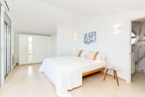 A modern bedroom with a large bed, a glass side table, and a marble wall. - Villa Alizee - Four Bedroom Villa, Sleeps 9 (Olèrdola)