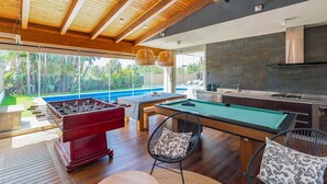 Cocina moderna con mesa de billar, mesa de fútbol de mesa y comedor con vista a una piscina.