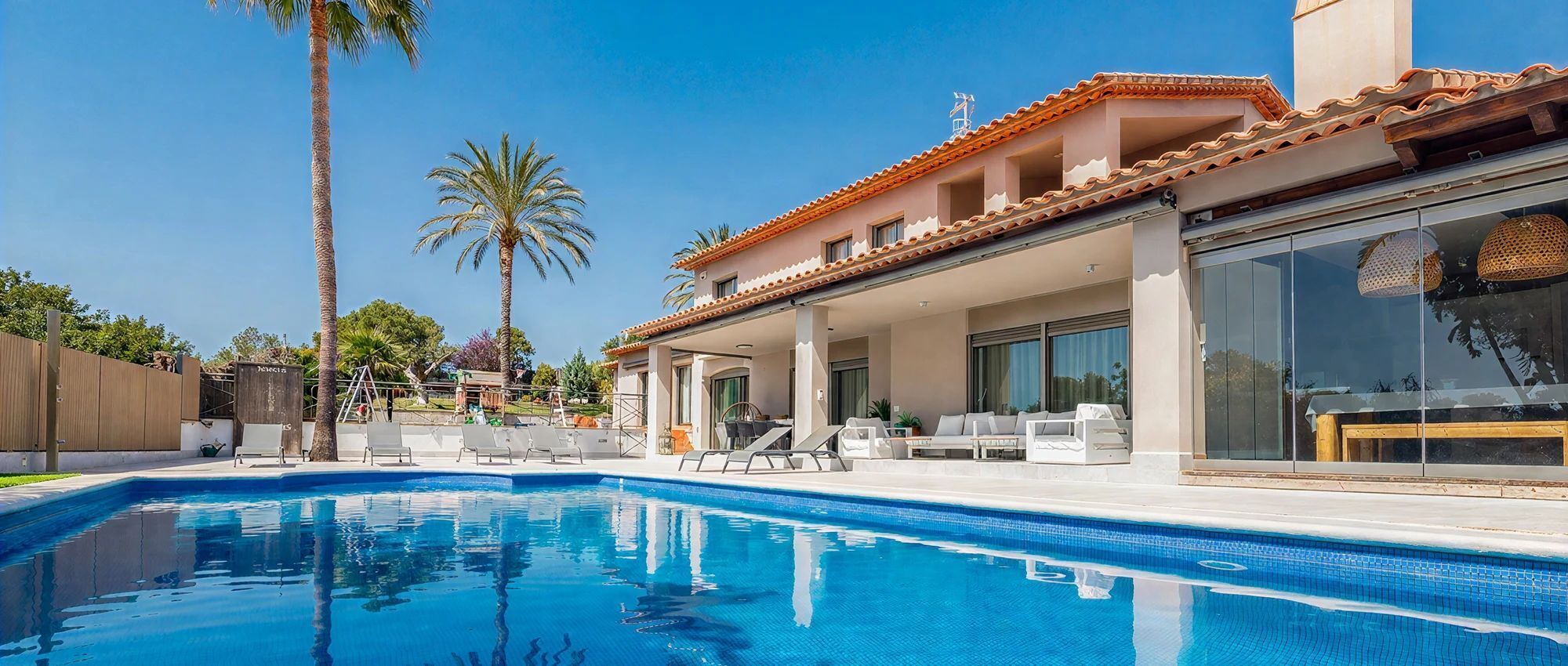 Ein Pool mit Liegestühlen und einer überdachten Terrasse.