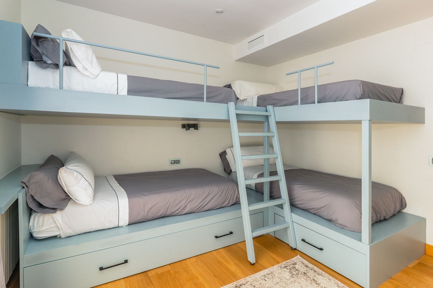 Dormitorio con literas, cajones y un radiador.