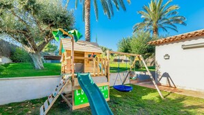 Una estructura de juego de madera con tobogán, columpios y una zona de escalada.