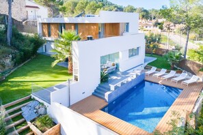 Ein modernes Haus mit Swimmingpool, Terrasse und Garten.