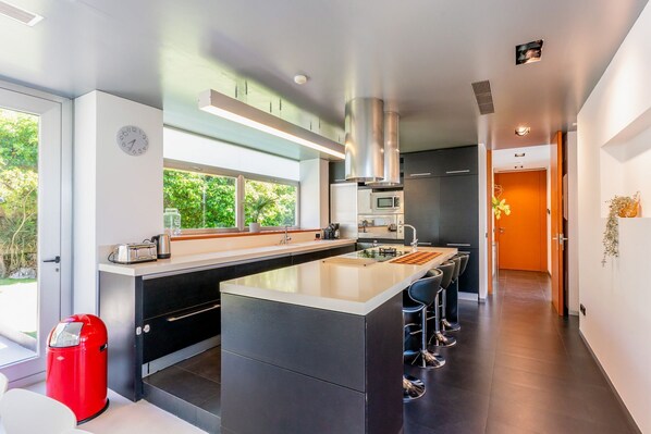 A modern kitchen with a central island, a microwave, and a sink. - Villa Arago - Six Bedroom Villa, Sleeps 12 (Sitges)