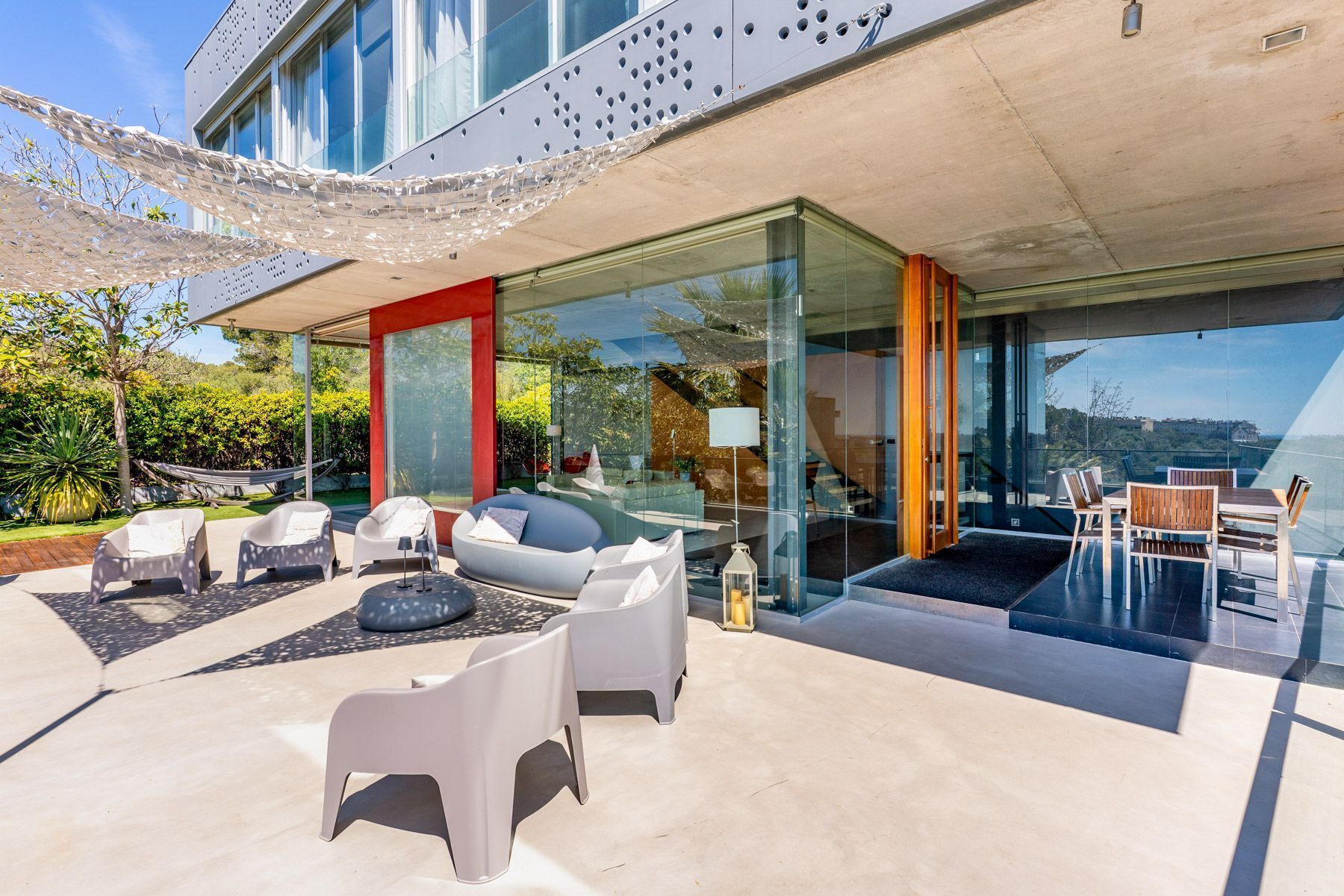Ein moderner Außenbereich mit Glaswänden, einem Pool und Gartenmöbeln.