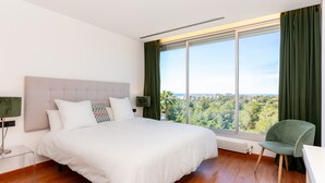 Ein Schlafzimmer mit einem großen Bett, Blick ins Freie und einem Sessel.