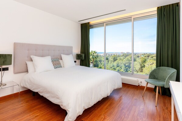Ein Schlafzimmer mit einem großen Bett, Blick ins Freie und einem Sessel.