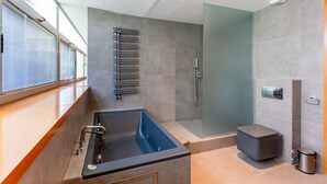 Een moderne badkamer met een bad, douche en toilet.