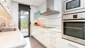 Una cocina moderna con armarios blancos, electrodomésticos de acero inoxidable y un ventanal amplio.