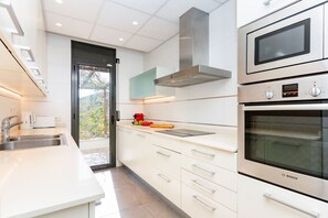 Eine moderne Küche mit weißen Schränken, Edelstahlgeräten und einem großen Fenster.