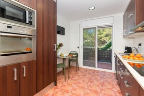 Eine kleine Küche mit Mikrowelle, Backofen und einem Essbereich mit Tisch und Stühlen.