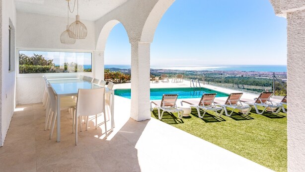 Una villa moderna con piscina, mobiliario de exterior y vistas al mar.