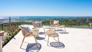 Una terraza con mobiliario exterior y una vista panorámica de la costa.