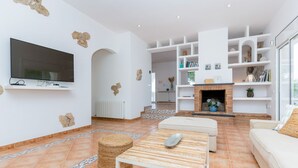 Una sala de estar con televisor, sofás, chimenea y estantería.