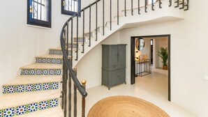 A spiral staircase with decorative tiles, a dark wooden cabinet, and a woven rug. - Villa Caliza I - Four Bedroom Villa, Sleeps 8 (Cunit)